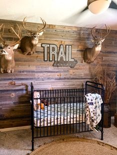 there is a baby crib with deer heads on the wall and another animal head mounted to the wall