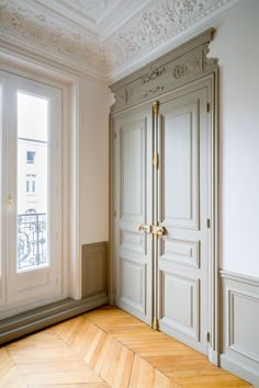 an empty room with wooden floors and white walls, decorated with gold trimmings