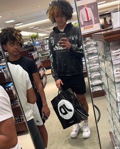 two men looking at their cell phones in a store