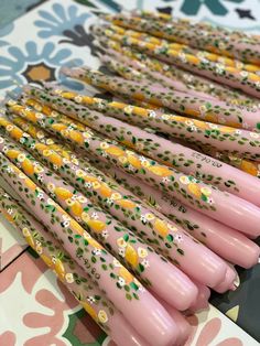 many pink and yellow plastic straws are lined up on a floral wallpapered table