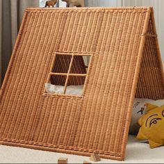 a wicker house with a stuffed animal in it's window and pillows on the floor