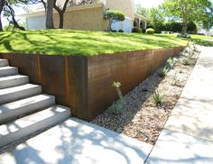 a large metal planter sitting on the side of a sidewalk next to a house