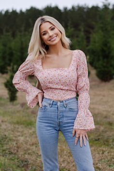 This is our gorgeous "In Full Bloom Top". From the smocked trumpet sleeves to the beautiful floral print, this blouse is ALL about the details. We suggest pairing it with our "Go Your Own Suede Shorts" or our "Zip it Skirt". The fit is true-to-size. The back can be tied and adjusted to your liking. Our model is 5'4", 112 pounds, and is wearing a size small. Spring Square Neck Printed Tops, Pink Floral Print Smocked Top With Long Sleeves, Pink Floral Print Smocked Long Sleeve Top, Pink Floral Print Long Sleeve Smocked Top, Long Sleeve Smocked Top With Floral Print For Brunch, Long Sleeve Floral Smocked Top For Brunch, Fitted Long Sleeve Blouse With Smocked Cuffs, Trendy Long Sleeve Smocked Top With Floral Print, Long Sleeve Smocked Top With Smocked Cuffs For Spring