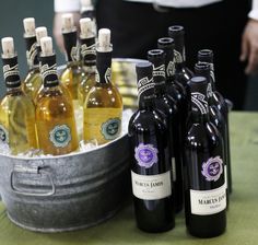 several bottles of wine are sitting in a bucket next to each other on a table