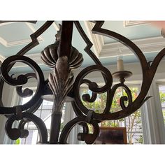 a chandelier hanging from the ceiling in front of a window with an ornate design