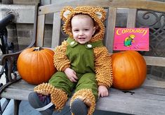 a baby sitting on a bench with some pumpkins