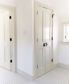 an empty room with two white doors and a black and white checkerboard floor