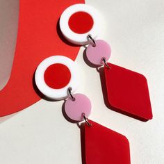 two pairs of red and white earrings sitting on top of a table next to each other