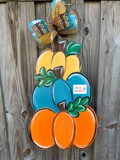 an orange and blue pumpkin door hanger on a wooden fence with two jars in the background