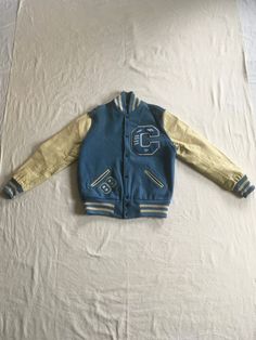 "vintage 1980s bomber jacket  light smoky blue  new wool Lasley knitting Co. Seattle WA  white leather sleeves gray lining  1989 patch C patch w/smaller sport/club patches side pockets ribbed stripe trim snap up front underarm 2 metal rivet vents good vintage condition, light overall wear including light stains, tiny seed size hole on shoulder/sleeve, ring around underside of collar, leather has aged patina-see photos label tag size 44-see below measures, lying flat, shoulder-19 1/2\" chest-24\" sleeve-26\" hem-18\" length at top shoulder next to neck-28 1/2\"" Winter Sporty Varsity Jacket With Patches, Sporty Winter Varsity Jacket With Patches, Winter Varsity Jacket With Patchwork, Retro Cotton Varsity Jacket With Patchwork, Collegiate Varsity Jacket With Patches For Winter, Collegiate Winter Varsity Jacket With Patches, Fitted Retro Cotton Varsity Jacket, Blue Varsity Jacket With Patchwork, Blue Patchwork Varsity Jacket