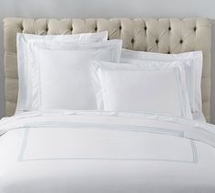 a bed with white sheets and pillows on top of it