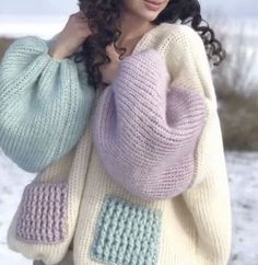 a woman wearing a sweater and hat in the snow with her hand on her shoulder