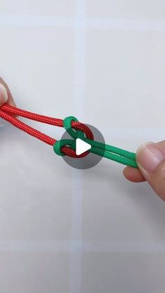 someone is tying a red and green string together