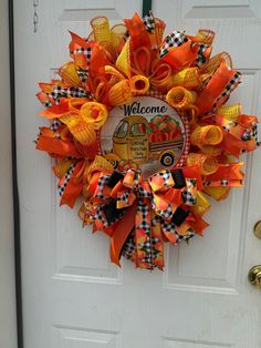 an orange and black wreath with the words welcome to our school bus is hanging on a white door