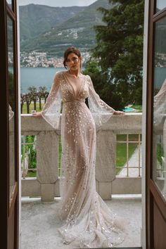 a woman in a long dress standing on a balcony