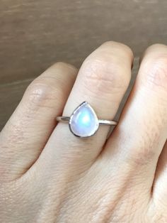 A Stackable pear-shaped smooth Rainbow Moonstone Sterling Silver Ring featuring a comfort fit band with a bezel around the stone and open back. This ring is small enough to stack with our other gemstone ring or makes a cool midi/thumb/pinky/knuckle/children ring for her. BELESAS and 925 hallmarked inside the ring. Wrapped in a box ready for gift giving.(r-c-310) RING INFO ---------------- STERLING SILVER June Birthstone Moonstone measure 7mmW x 9mmL Stackable Ring Model ring size 5 *Please note Teardrop Moonstone Gemstone Ring, Adjustable Teardrop Moonstone Ring In Sterling Silver, Silver Teardrop Moonstone Ring, Teardrop Moonstone Promise Ring, Adjustable Teardrop Crystal Ring With Gemstone, Spiritual Moonstone Teardrop Ring, Teardrop Moonstone Ring For Anniversary, Teardrop Moonstone Ring, Teardrop Moonstone Ring Adjustable For Gift