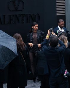 people are standing outside with umbrellas in the rain and one person is holding an umbrella