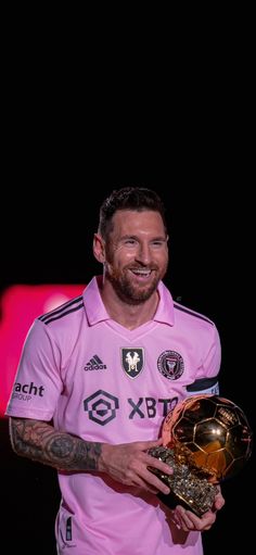 a man holding a soccer ball and trophy