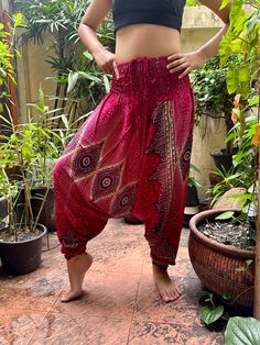 a woman is standing in front of some plants and potted plants, with her hands on her hips