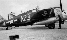 an old black and white photo of a fighter plane on the tarmac with two men standing next to it