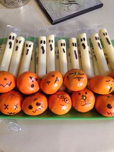 oranges with faces drawn on them are lined up in a row next to candles