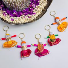 four small pieces of colorful fabric hanging from metal hooks on a white surface next to flowers