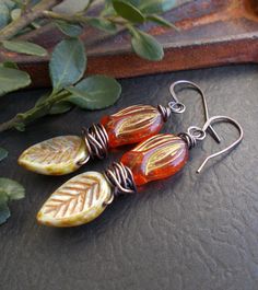 "Colorful woodland earrings featuring beautiful Czech glass beads. The flower drops are a bright koi orange with a rustic gold metallic finish. The leaves are light green with a terracotta and caramel finish. I've wrapped the beads with solid copper wire which I have oxidized. I made matching solid copper ear wires. These earrings are a fun addition to your boho collection and a great gift for someone who loves nature or rustic style. You can select copper niobium or copper plated lever back ear Orange Czech Glass Jewelry With Ear Wire, Artistic Orange Jewelry With Matching Earrings, Nickel-free Orange Flower Earrings, Orange Adjustable Dangle Flower Earrings, Orange Bohemian Flower Earrings For Gift, Bohemian Orange Flower Earrings For Gift, Unique Orange Flower-shaped Jewelry, Artistic Orange Dangle Jewelry, Unique Orange Flower Shaped Jewelry