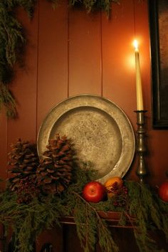 a candle is lit next to a plate with pine cones on it