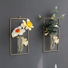 two vases with flowers are hanging on the wall next to each other in front of a gray wall