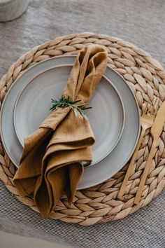 a place setting with napkins and silverware on a wicker tableclothed place mat