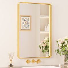 a bathroom sink sitting under a mirror next to a vase with flowers on top of it