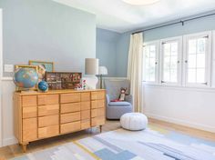 a living room with blue walls and wooden furniture in the corner, along with a white rug on the floor