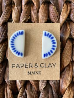 a pair of blue and white ceramic earrings sitting on top of a piece of paper