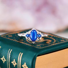 a blue stone ring sitting on top of a book