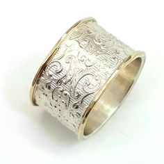 a gold and silver ring with intricate designs on the inside, sitting on a white surface