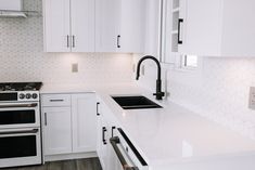 a white kitchen with an oven, sink and stove top in it's center island