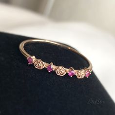 We can't travel back the time but we can adore this Art Nouveau inspired, artisan carved rose ring embraced with natural ruby handcrafted in 9K solid gold. Ships within 3 business days. - Stone info: natural round cut ruby - Stone size: 1.5mm x 4pcs - Band width: 2mm - Made in 9 karat gold. - Stamp with 9K. Rose Gold Ruby Ring In Fine Jewelry Style, Rose Gold Ruby Ring For Promise, Rose Gold Ruby Promise Ring With Rose Cut Diamonds, Rose Gold Ruby Ring As Gift, Rose Gold Ruby Ring Gift, Rose Ring, Ruby Stone, Ruby Rose, Natural Ruby