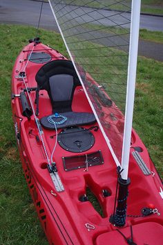 a red kayak sitting on top of a lush green field