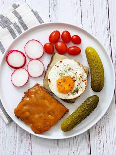 a white plate topped with toast, pickles and an egg