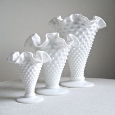 three white vases sitting on top of a table