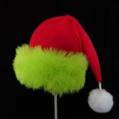 "This festive Santa hat is made up in a red fleece fabric and features an accent brim of a soft lush bright green fur trim, close match to a Grinch green. The red fabric is a soft quality poly fleece fabric, cozy and warm. Proportions of the hat are generous and will fit most head sizes, ladies or gents. The styling is a slouch cone, traditional Santa look. Measurement for opening for your head is 24- 25\" circumference and the length is 20\". There is a white faux fur pompom dangle on the hat." Green Brimmed Winter Costume Hats, Green Winter Costume Hats And Headpieces, Grinch Hat, Kids Santa Hat, Christmas Party Hat, Christmas Party Hats, Green Santa, Red Green Christmas, Green Fur