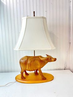 a wooden animal lamp with a white shade