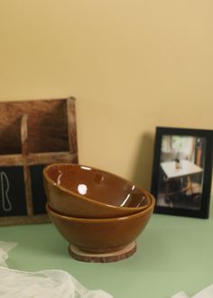 two wooden bowls sitting on top of a table next to a framed photo and other items