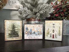 three christmas cards on a table next to a potted plant and some other decorations