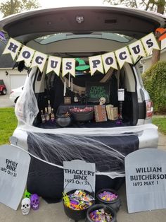 the trunk of a van decorated for halloween with decorations and signs in front of it