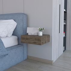 a bed with a blue headboard and white pillows next to a small wooden table