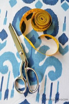 a pair of scissors sitting on top of a blue and white table cloth next to a measuring tape