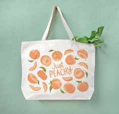 a white bag with oranges on it that says just peachy hanging from a wall