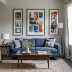 a living room with blue couches and pictures on the wall above them, along with a coffee table