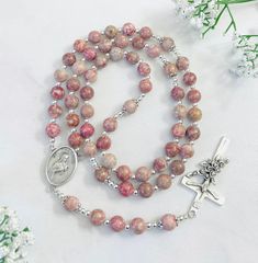 "This beautiful Saint Therese rosary is made of Maifan Stone Gemstone Beads Materials:  * 8mm Maifanite Stone Gemstone stone beads * Spacer beads and bead caps * Saint Therese medal centerpiece, made in Italy * Beautiful Rose crucifix made in Italy For personalization: 💛  If you want to change the centerpiece and crucifix, please mention its number in the \"Personalization box\", otherwise I will make your rosary same as in the listing pictures.  ❤️ Name/initial can be added on the rosary by adding letter beads. Please let me know the name(s)/initial(s). If one name is added, the name goes in the middle of the 3rd decade.  If two names are added,  the names go in the middle of 2nd and 3rd decades. If three names are added, the names go in the middle of 2nd, 3rd, and 4th decades. If four n Gift Rosary Bracelet With 8mm Beads And Crucifix, Silver Rosary Bracelet With Gemstone Beads As Gift, Gift Rosary Bracelet With Polished Beads, Adjustable Rosary With Oval Beads As Gift, Gift Round Rosary Bracelet With Polished Beads, Silver Rosary Bracelet With Gemstone Beads, Round Beads Rosary With Natural Stones For Gift, Gemstone Beads Rosary As Gift, Rosary With 8mm Round Beads As Gift